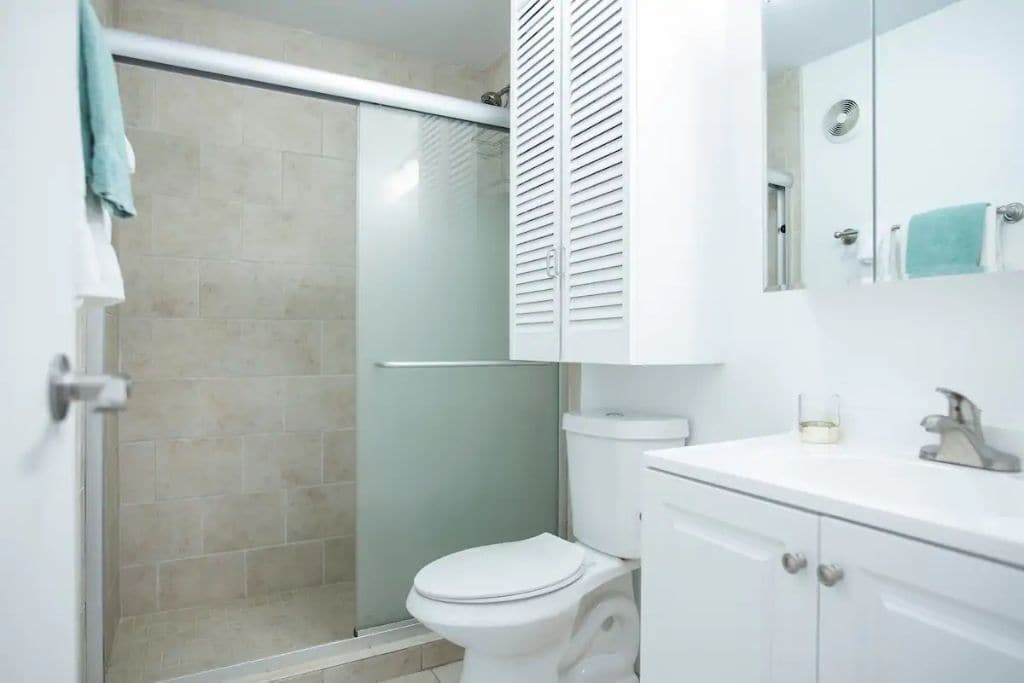 Une salle de bain avec une douche à parois de verre, des toilettes et un lavabo avec un miroir au-dessus.
