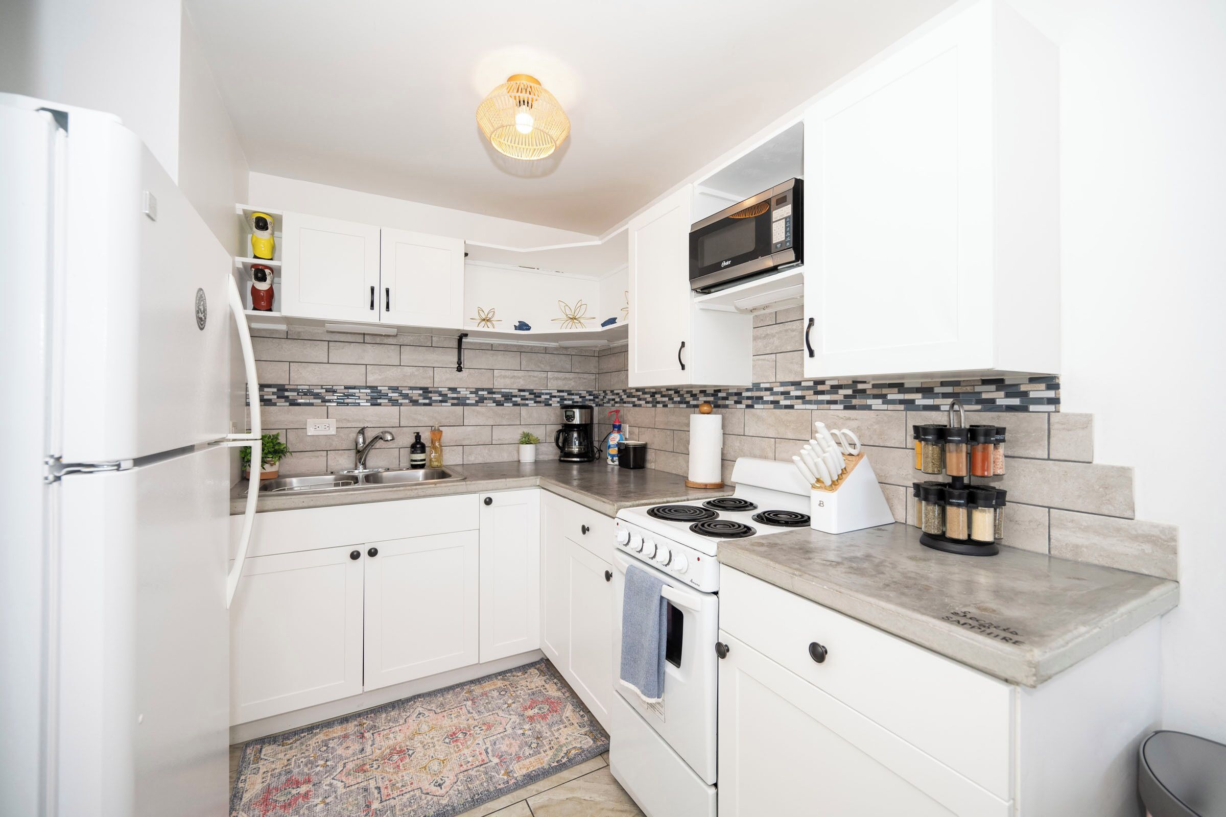 A modern kitchen with white cabinets, a stove, a microwave, and a coffee maker.