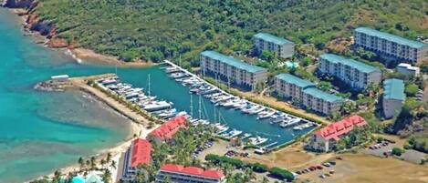 An aerial view of a coastal hotel with multiple buildings, a marina with boats, and a beach area.