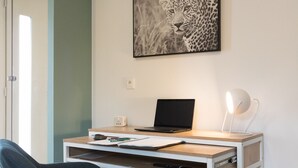 Un'area di lavoro moderna con scrivania, portatile e un'opera d'arte con motivo leopardato al muro.