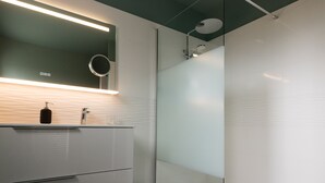 Un bagno moderno con cabina doccia in vetro, uno specchio sopra il lavabo e un water.