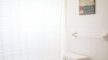 Een bad/douchecombinatie, een haardroger, handdoeken