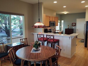 A modern kitchen with wooden cabinets, a microwave, and a dining area with a round table and chairs. - Beautiful, secure, private townhouse in Silverdale. (Silverdale)