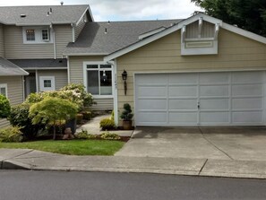 A two-story house with a garage, a front porch, and a well-maintained lawn. - Beautiful, secure, private townhouse in Silverdale. (Silverdale)