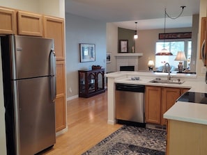 A modern kitchen with wooden cabinets, stainless steel appliances, a dishwasher, and a built-in oven. - Beautiful, secure, private townhouse in Silverdale. (Silverdale)