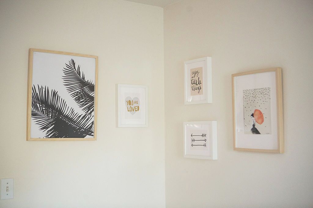 Una pared con cuatro obras de arte enmarcadas, incluyendo un diseño de hoja de palma e ilustración de un pájaro.