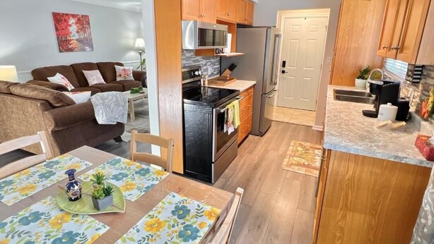 Una cucina moderna con mobili in legno, elettrodomestici in acciaio inossidabile e un'area pranzo con tovaglia a fiori.