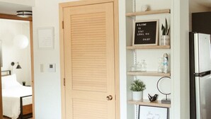 A modern living room with a wooden door, a sofa, a coffee table, and a bookshelf with various items.