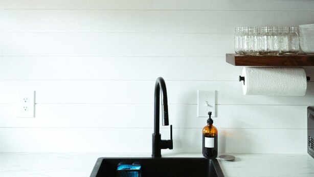 A modern kitchen with a black faucet, a wine bottle, and a hanging light fixture. - Modern, Warm, Chic Flat in Westerville (Westerville)