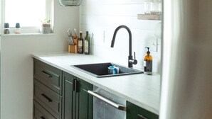 A kitchen with a black faucet, wooden cabinets, a white countertop, and a hanging light fixture. - Modern, Warm, Chic Flat in Westerville (Westerville)