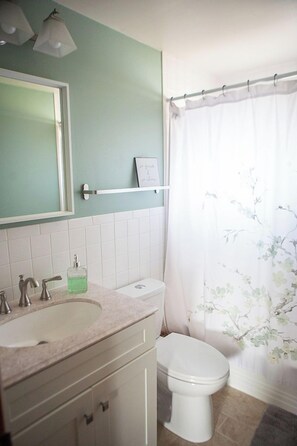 A bathroom with a sink, toilet, and shower curtain. - Bright, Modern Townhome with Natural Light (Westerville)