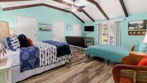A bedroom with a bed, a desk, a chair, a TV, and a window.