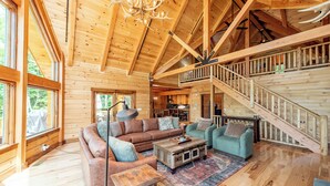 A spacious wooden cabin with a large living area, a staircase, and a dining area. - Luxury Deep Creek Stay w/ Fire Pit & Views (Swanton)