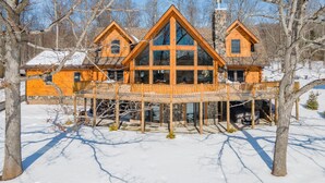 A log cabin with a large glass front and a wooden deck. - Luxury Deep Creek Stay w/ Fire Pit & Views (Swanton)