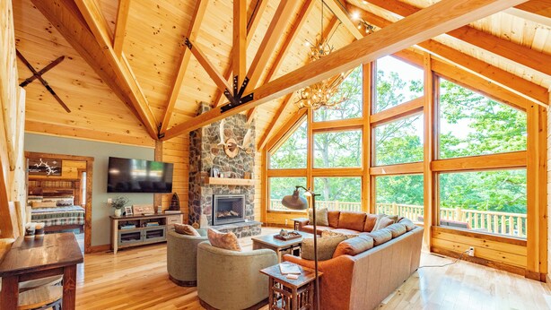 A wooden interior with a stone fireplace, a large window, and a cozy seating area. - Luxury Deep Creek Stay w/ Fire Pit & Views (Swanton)