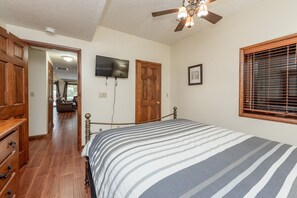A bedroom with a bed, wooden wardrobe, ceiling fan, TV, and a window with blinds. - Cozy Lake Escape Near State Park & Slopes (Swanton)