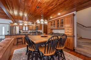 A spacious kitchen with wooden cabinets, a large island, and a dining area with chairs. - Cozy Lake Escape Near State Park & Slopes (Swanton)