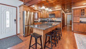 A spacious kitchen with wooden cabinets, stainless steel appliances, and a central island with stools. - Cozy Lake Escape Near State Park & Slopes (Swanton)