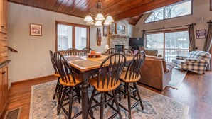 A dining area with a wooden table and chairs, a chandelier, and a fireplace. - Cozy Lake Escape Near State Park & Slopes (Swanton)