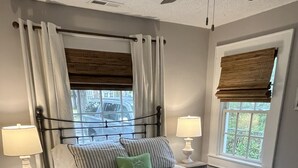 Ein Schlafzimmer mit einem Bett, zwei Nachttischen mit Lampen, einem Fenster mit Blick und einem gemusterten Teppich.