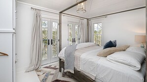 Ein Schlafzimmer mit Himmelbett, großen Fenstern und einer Kronleuchter.