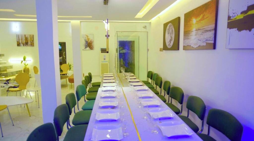 Une salle de conférence avec une longue table préparée pour une réunion, entourée de chaises vertes.