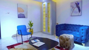 A modern living room with a blue sofa, a blue armchair, a coffee table, and a cabinet with glass doors.