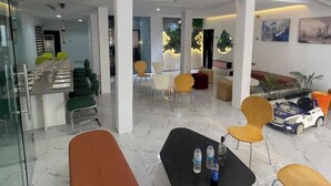 A modern hotel lobby with a dining area, seating arrangements, and a toy car display.