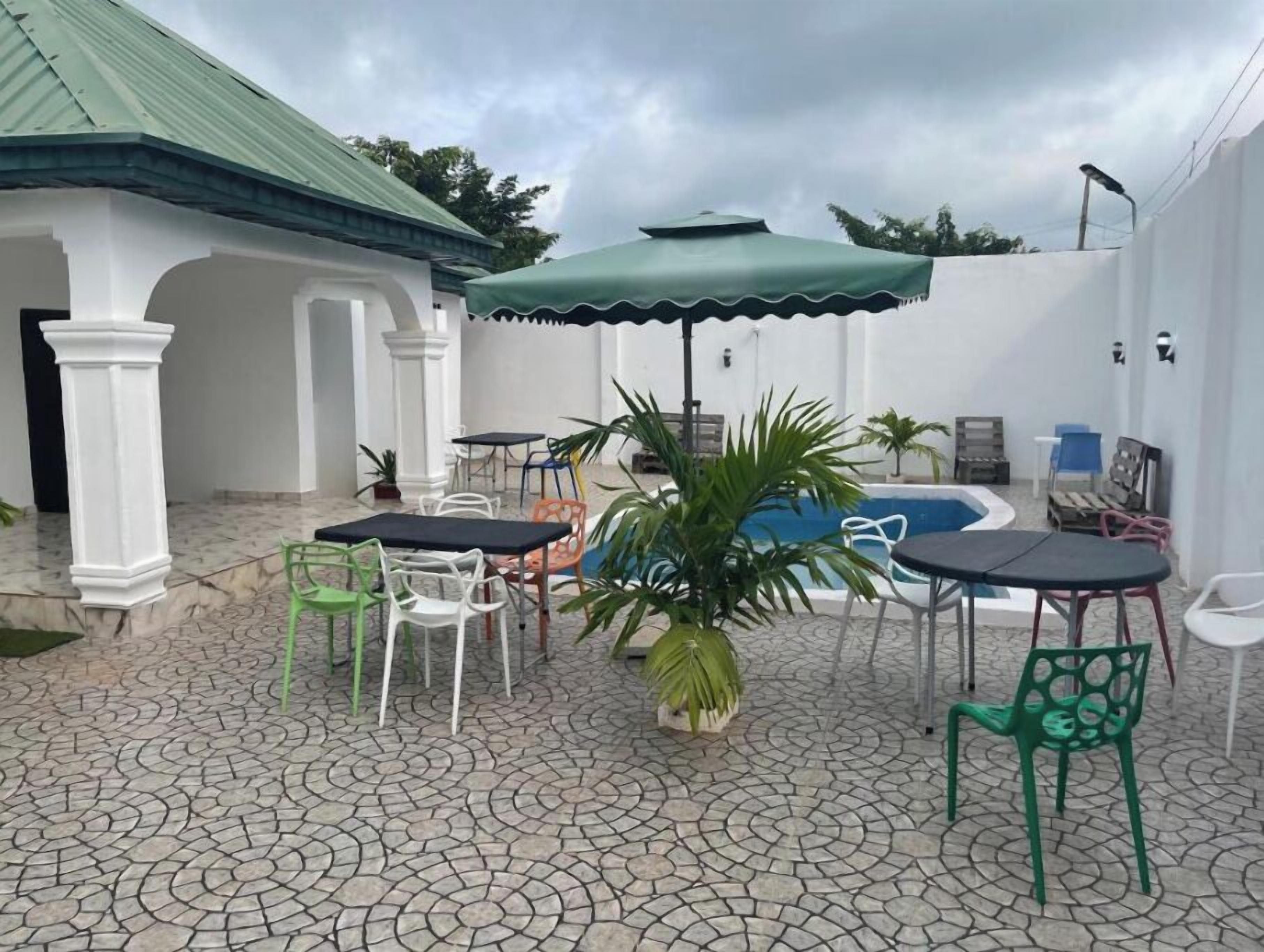 Un patio con mesas y sillas, una piscina y una zona de estar cubierta.