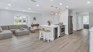 Een moderne keuken met witte kasten, roestvrijstalen apparatuur en een centraal eiland met krukken.