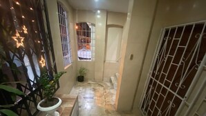 A hallway with a tiled floor, a potted plant, and a barred gate. - Departamento En La Garzota a  5 mnts del Aeropuerto (Guayaquil)