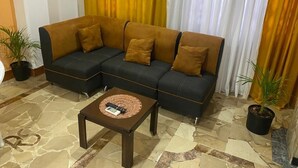 A sectional sofa with multiple cushions, a coffee table with a remote control, and potted plants. - Departamento En La Garzota a  5 mnts del Aeropuerto (Guayaquil)