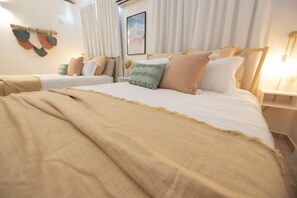 Hotelkamer met twee bedden, beige beddengoed, een wanddecoratie en een nachtkastje met een lamp.