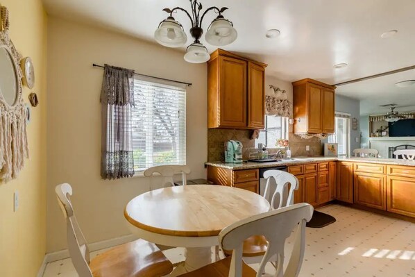 Enjoy meals around the central dining table in this cozy kitchen, equipped with a stove and wooden cabinets.