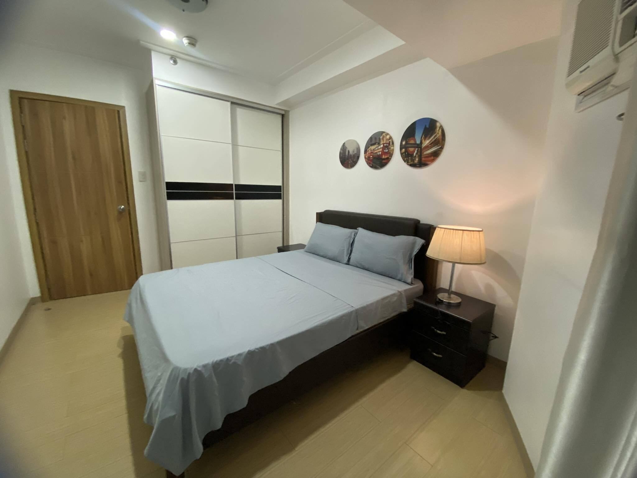 A bedroom with a bed, nightstand, and wall art.