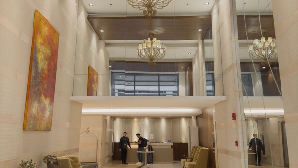 A spacious lobby with a high ceiling, modern chandeliers, a reception desk, and comfortable seating areas.