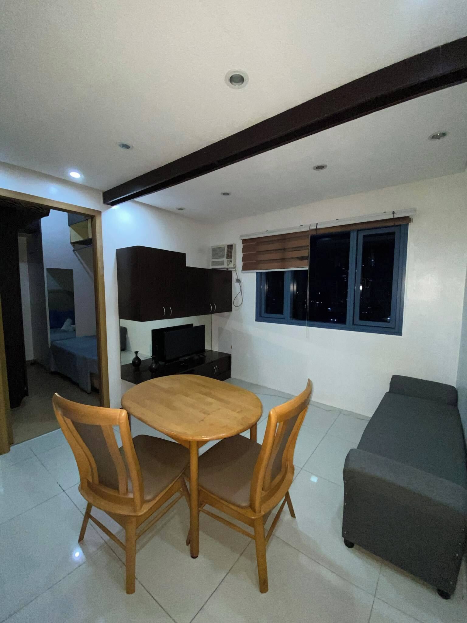 Un espacio habitable compacto con comedor, kitchenette y ventana con persianas.