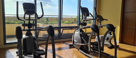 Un gimnasio con máquinas de cardio y vistas a zonas verdes a través de amplios ventanales.