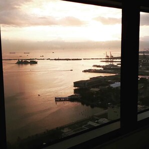 A view of a harbor with ships and cranes, buildings, and a dock.