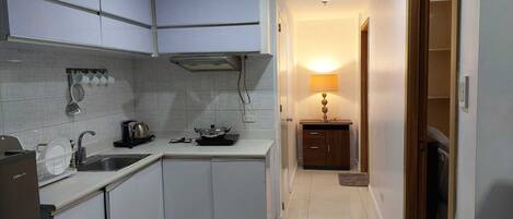 A compact kitchen with white cabinets, a built-in stove, and a small countertop.