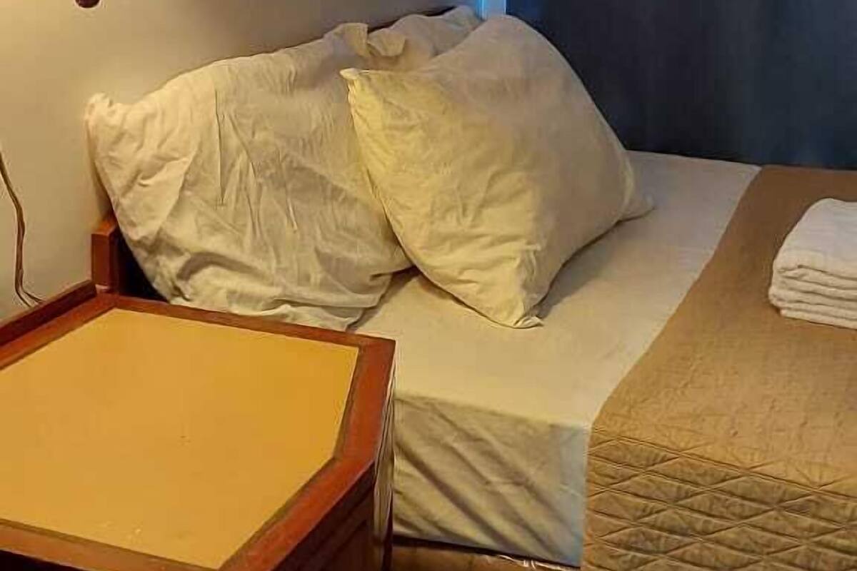 A hotel room with a bed, a bedside table, a lamp, and a window with curtains.