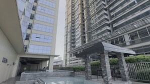 A modern high-rise building with a swimming pool and a covered patio area.