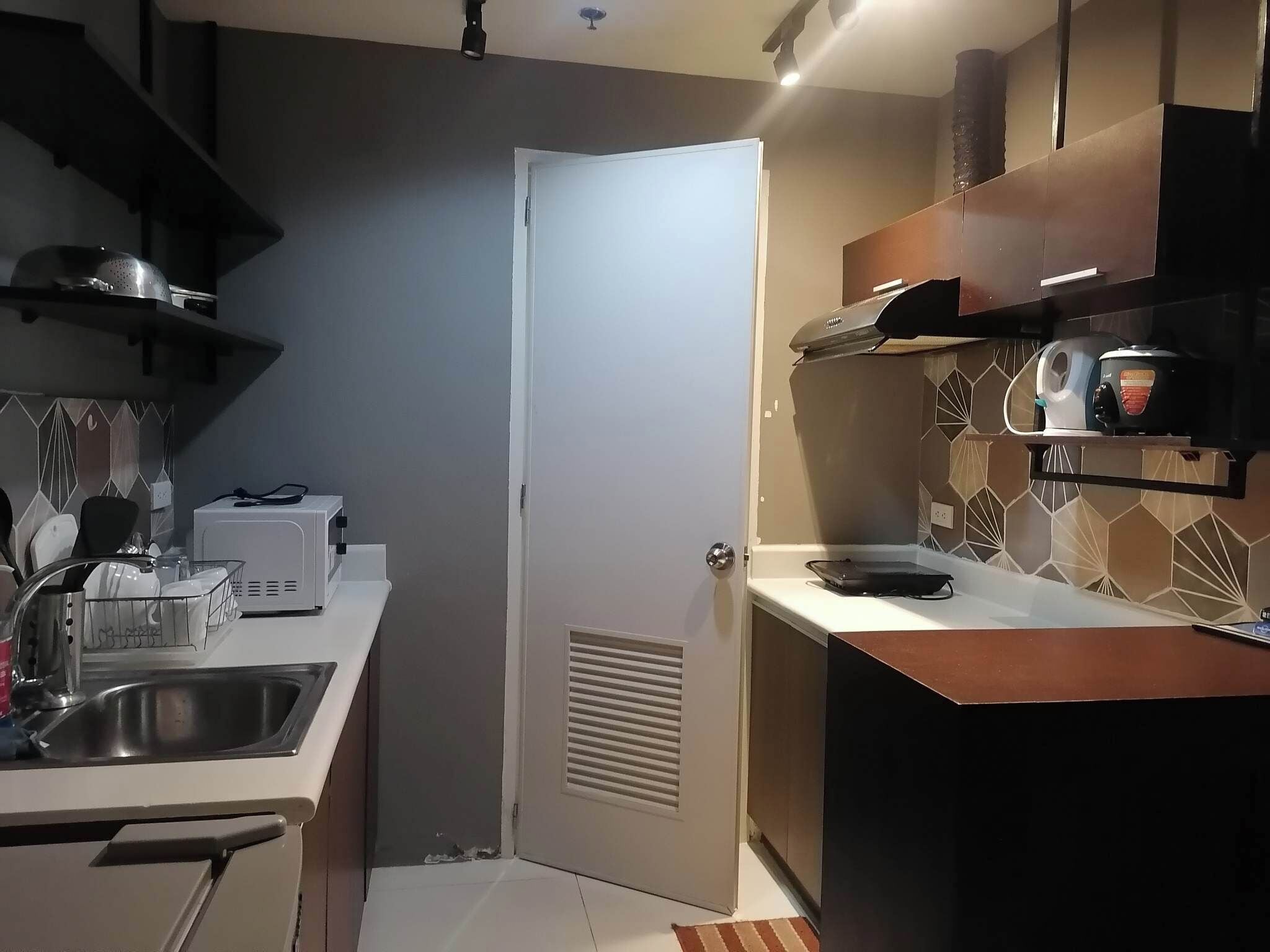 Cocina compacta con puerta blanca, un lavamanos, un microondas y una estufa.