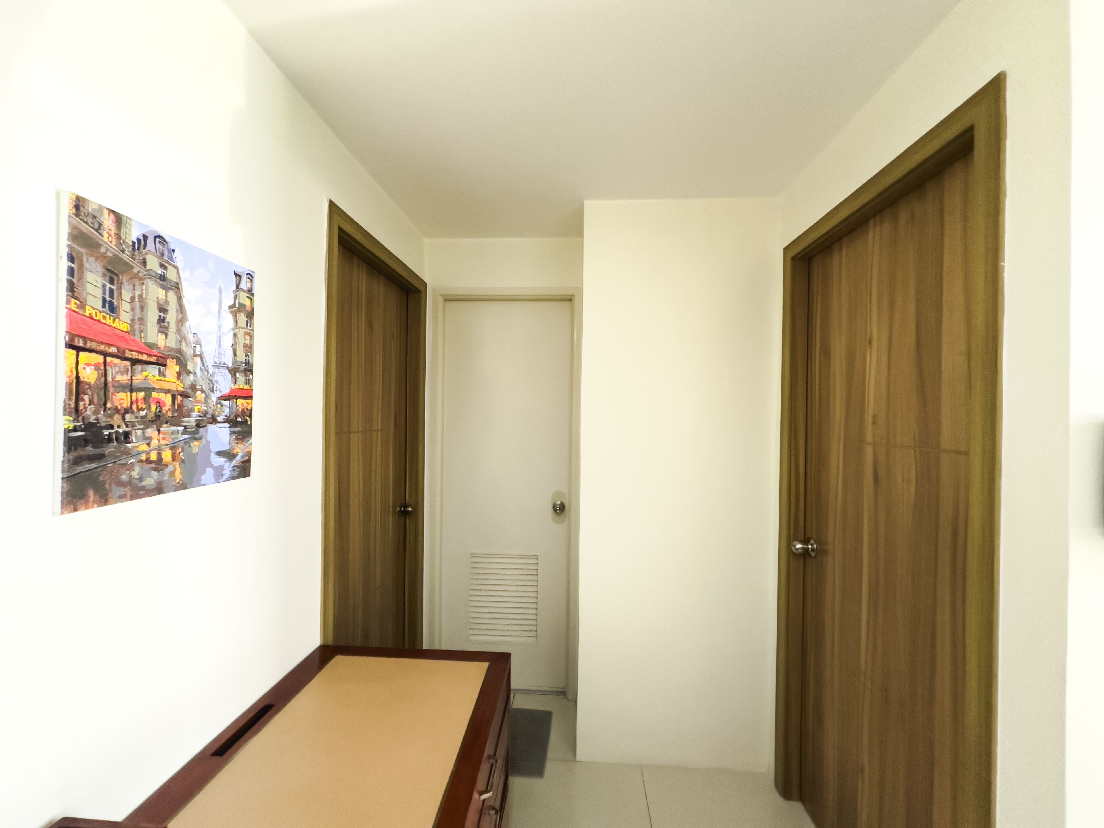 A narrow hallway with wooden doors and a billiards table.