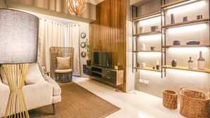 A modern living room with a sofa, television, and decorative shelves.
