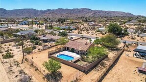 An aerial view of a residential area with houses, a swimming pool, and a hilly landscape in the background. - The Peaceful Retreat (5 min from the park entrance w/ Pool! (Joshua Tree)