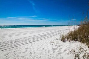 A sandy beach with a clear blue sky and ocean.