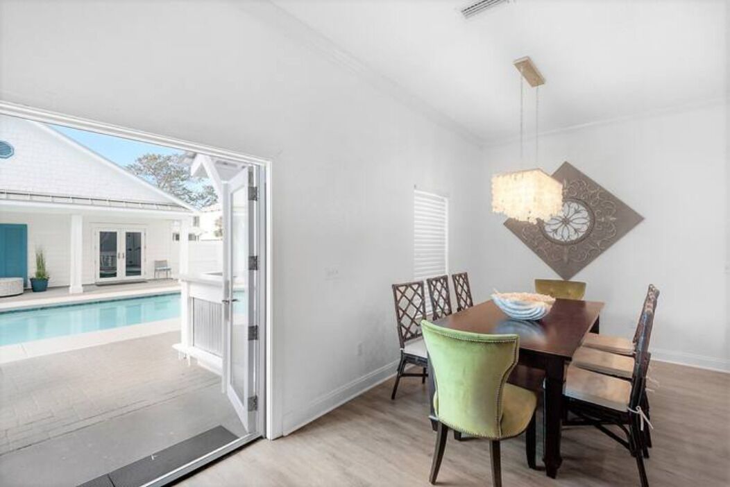 A dining area with a pool view, a sliding glass door, and a chandelier.