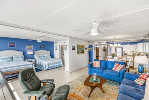 Una habitación moderna y bien iluminada con una cama grande, un sofá azul y un comedor.