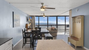 A spacious room with a dining area, a sofa, a bench, and a view of the ocean. - Gulf Shores Condo 403 Gorgeous 4th Floor Beachfront View (Port Aransas)